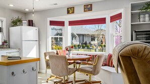 A modern kitchen with white cabinets and a built-in refrigerator. There is a dining area with a round table and two chairs. - The Cunningham Cottage | King Bed & Garden (Springfield)