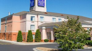 Ein Sleep Inn Hotel mit einem markanten Turm-Schild, einem Haupteingang und einem Parkplatz.