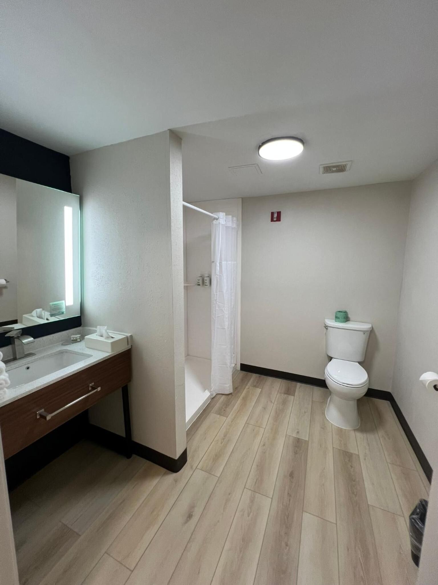 Un baño con lavamanos, espejo, inodoro y cortina de ducha.
