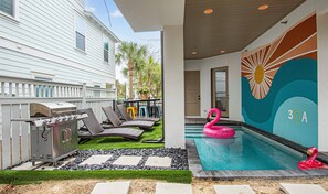 A pool area with a flamingo float, a grill, and lounge chairs. - 30A Luxury New Build| Private Htd Pool | Views | Steps to Beach|Golf Cart |Bikes (Santa Rosa Beach)