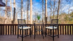 A wooden deck with two chairs and a table, surrounded by a wooden railing, overlooking a forested area. - Cozy Home:  Close to UT, Smoky Mountains and outdoor fun  (Knoxville)