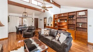 A spacious living room with a leather sofa, wooden bookshelves, and a dining area with a table and chairs. - Cozy Home:  Close to UT, Smoky Mountains and outdoor fun  (Knoxville)