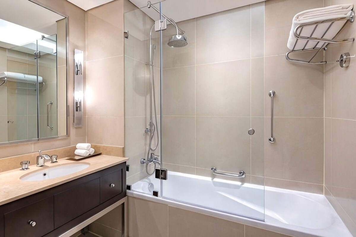 A modern bathroom with a glass-enclosed shower, a bathtub, and a vanity with a sink and mirror.