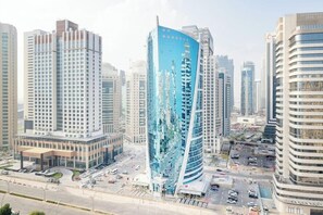 A modern high-rise building with a distinctive curved facade and a central atrium. - Qabila Westbay Hotel by Marriott (Doha)
