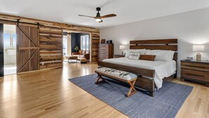 A spacious bedroom with a large bed, wooden headboard, and a sliding barn door closet.