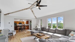 A spacious living room with a grey sofa, a wooden coffee table, and a ceiling fan.