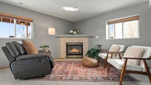 Una sala de estar con chimenea, un sillón reclinable, un sofá y una alfombra.