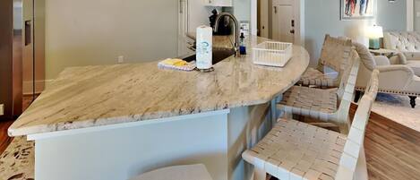A kitchen with a marble countertop, white cabinets, and a built-in bench.