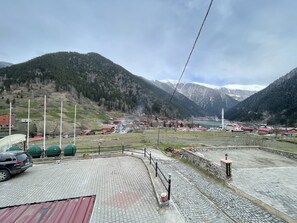 Ein gepflasterter Bereich mit einer Steinmauer, einem kleinen Gebäude und einer Fahnenstange.