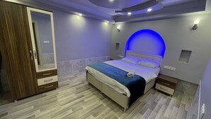 A modern bedroom with a bed, nightstands, a wardrobe, and a unique blue-lit arch on the wall. - Uzungöl Bikka Pansiyon (Çaykara)