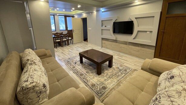 A modern living room with a sofa set, a coffee table, and a flat-screen TV mounted on the wall. - Uzungöl Bikka Pansiyon (Çaykara)