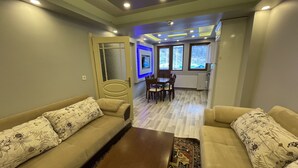 A living room with two sofas, a coffee table, and a dining area with a table and chairs. - Uzungöl Bikka Pansiyon (Çaykara)
