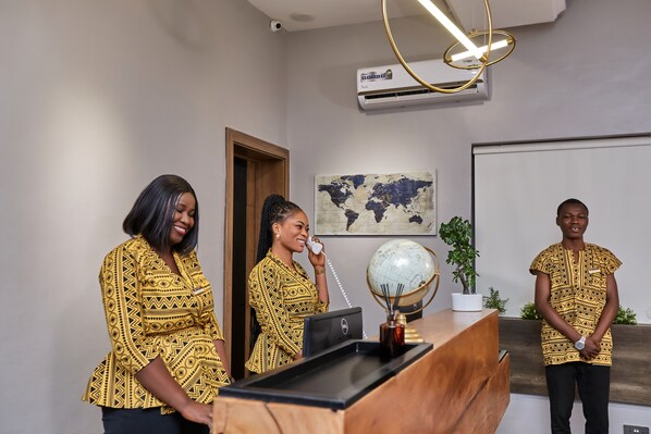 A reception desk with a globe, a laptop, and a potted plant.