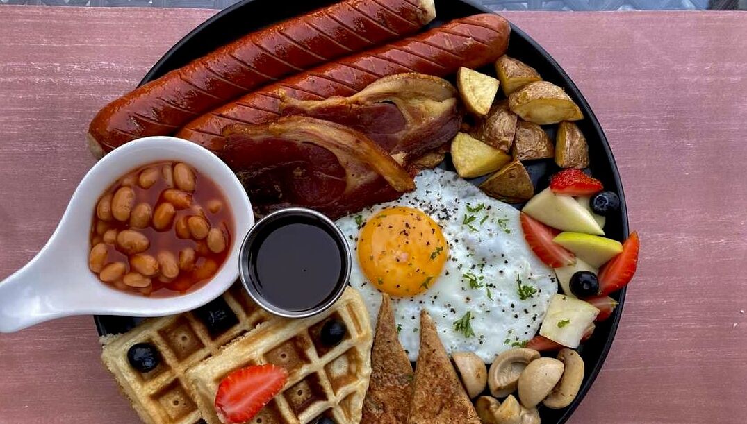 Un plato con salchichas, huevos, tostadas y frijoles.