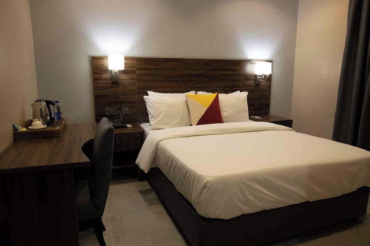 Une chambre d’hôtel comprenant un lit, une table de chevet, une lampe et un bureau avec une chaise.