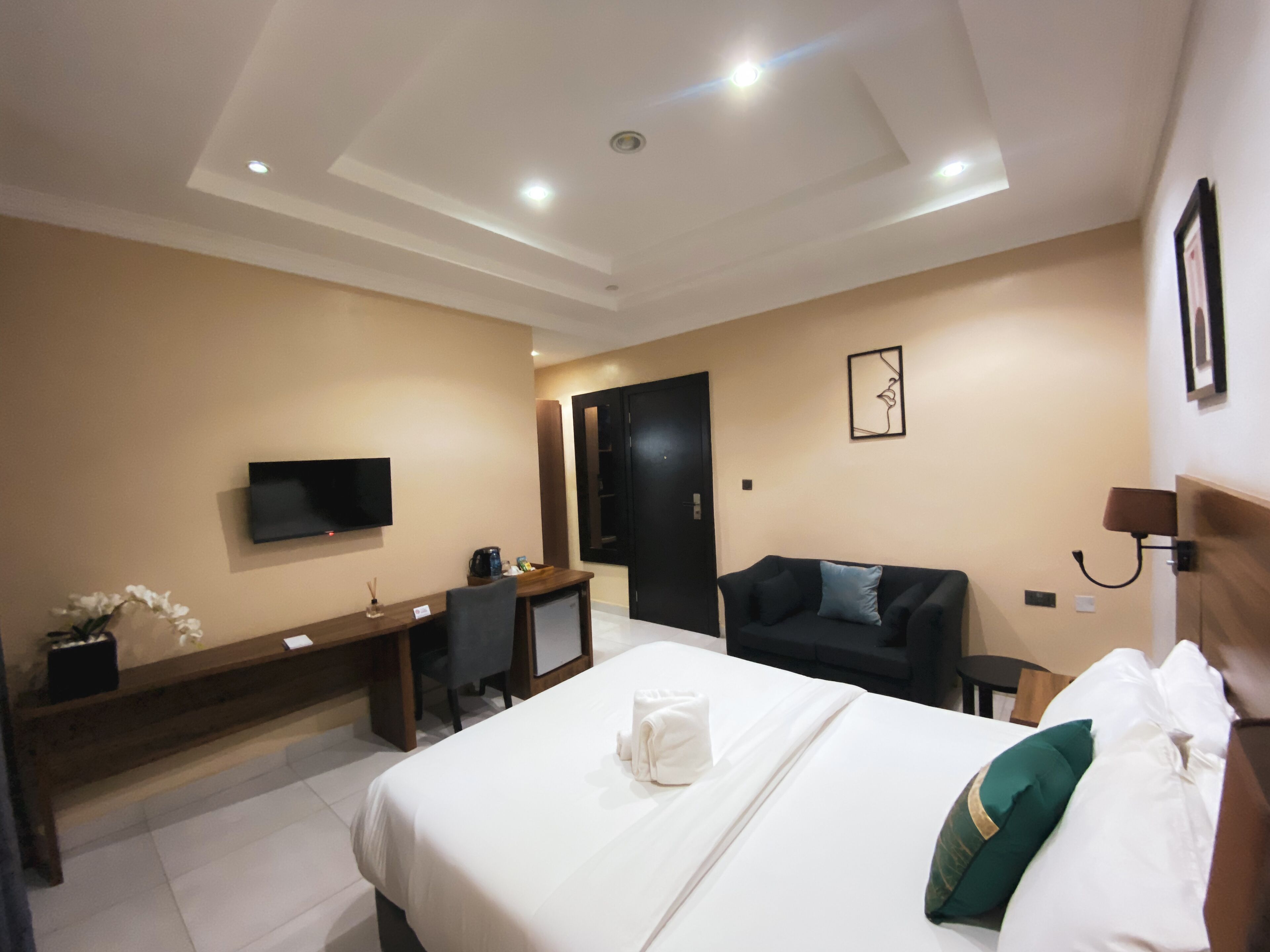 Una habitación de hotel con cama, escritorio, televisor y sofá.