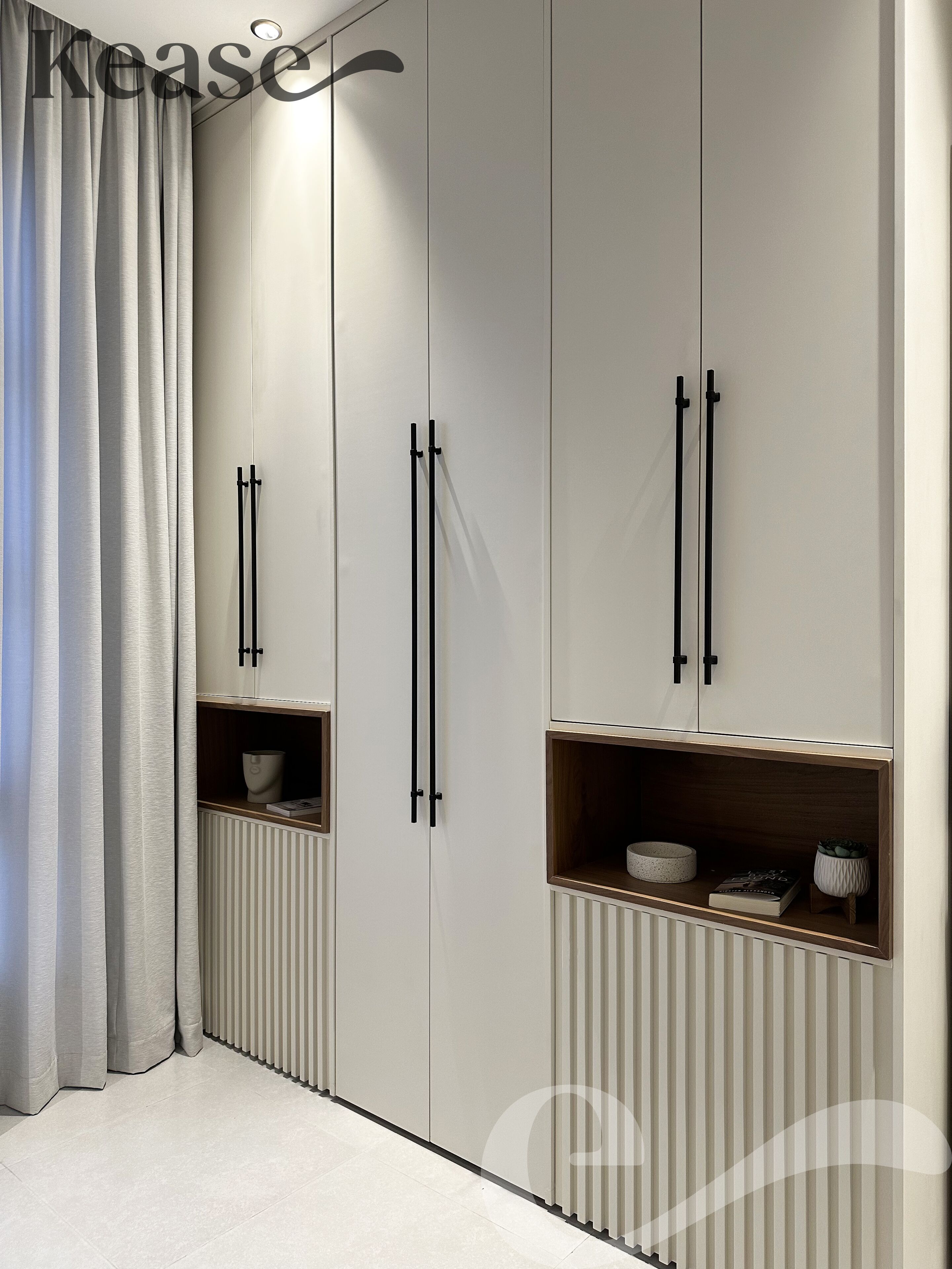 A wardrobe with two doors, each with a black handle, and a shelf with a bowl and a book.