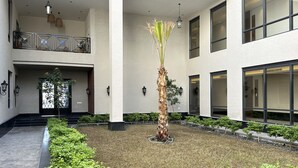 A spacious courtyard with a central palm tree, surrounded by small shrubs and a stone pathway. - Ar Rabi H-10 Royal touch Balcony AG98 (Riyadh)