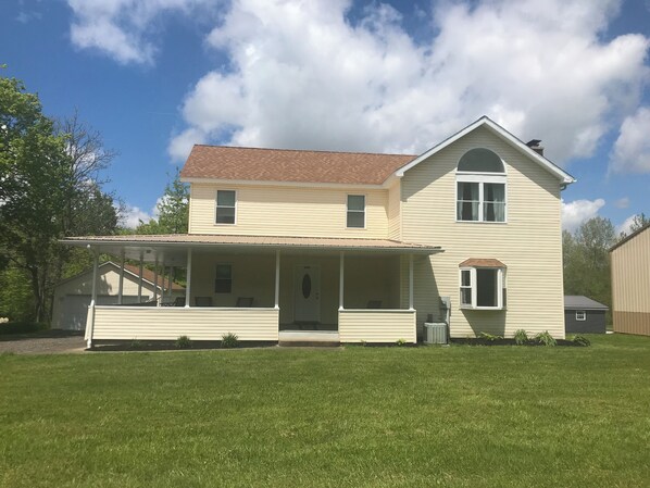 A two-story house with a porch, a small attached garage, and a well-maintained lawn.