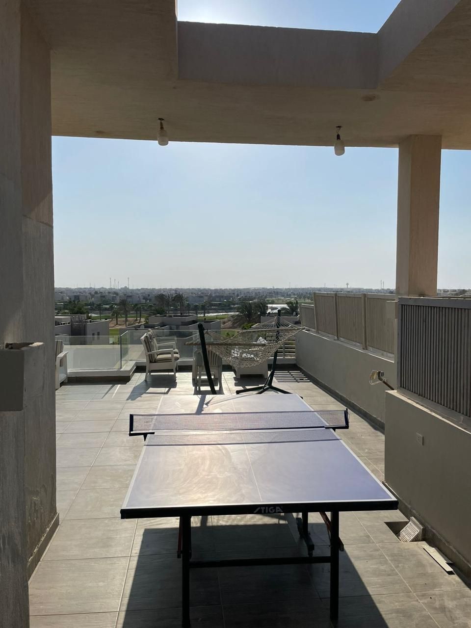 Terraza en la azotea con mesa de ping pong, sillas y una hamaca.