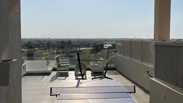 Terraza en la azotea con mesa de ping pong, sillas y una hamaca.