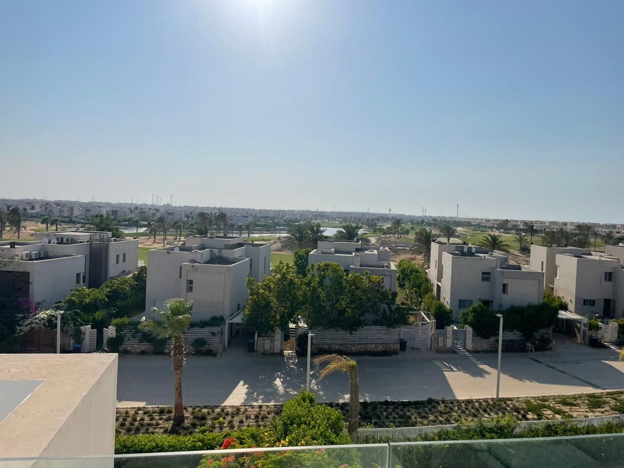 Un quartier résidentiel avec des bâtiments modernes, un ciel dégagé et un jardin bien entretenu.