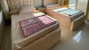 A spacious bedroom with two beds, a large mirror, and a balcony with a view. - Golfview House HaciendaBay Families Only (El Alamein)