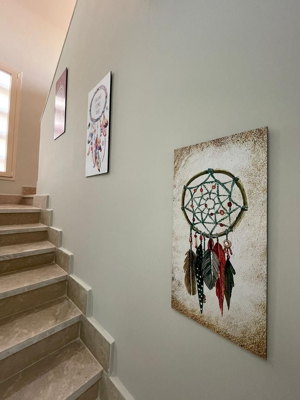 Een trap met een dromenvanger kunstwerk aan de muur.