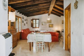 Une pièce chaleureuse avec un plafond en bois, une table à manger avec des chaises, un canapé et un lit.