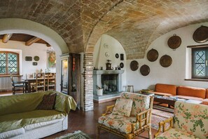 Un intérieur rustique avec un plafond en pierre, une cheminée, un coin repas et un salon meublé.