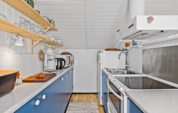 A compact kitchen with a sink, stove, and microwave. There are shelves with jars and a coffee maker. - Nice home in Vejby with WiFi (Vejby)