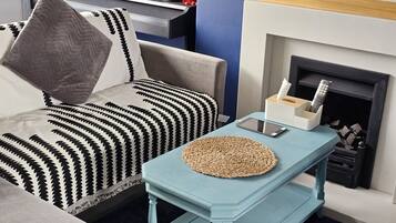 A living room with a sofa, a coffee table, a fireplace, and a television.