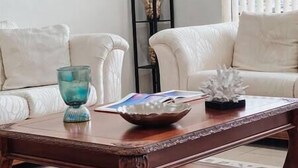 A wooden coffee table with a bowl and a book, a glass candle holder, and a decorative coral piece. - Family Fun, Pool,Theater, Backyard, Early Check-in (Palm Bay)