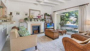 Una sala de estar con chimenea, muebles de mimbre y televisor.