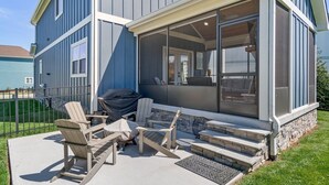 A house with a covered patio, outdoor seating, and a barbecue grill.