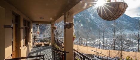 A balcony with a view of snow-covered mountains, potted plants, and a hanging basket.