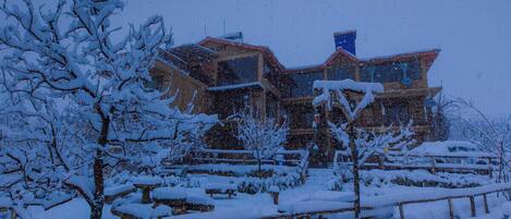 A snow-covered building with multiple levels and a complex roof structure.