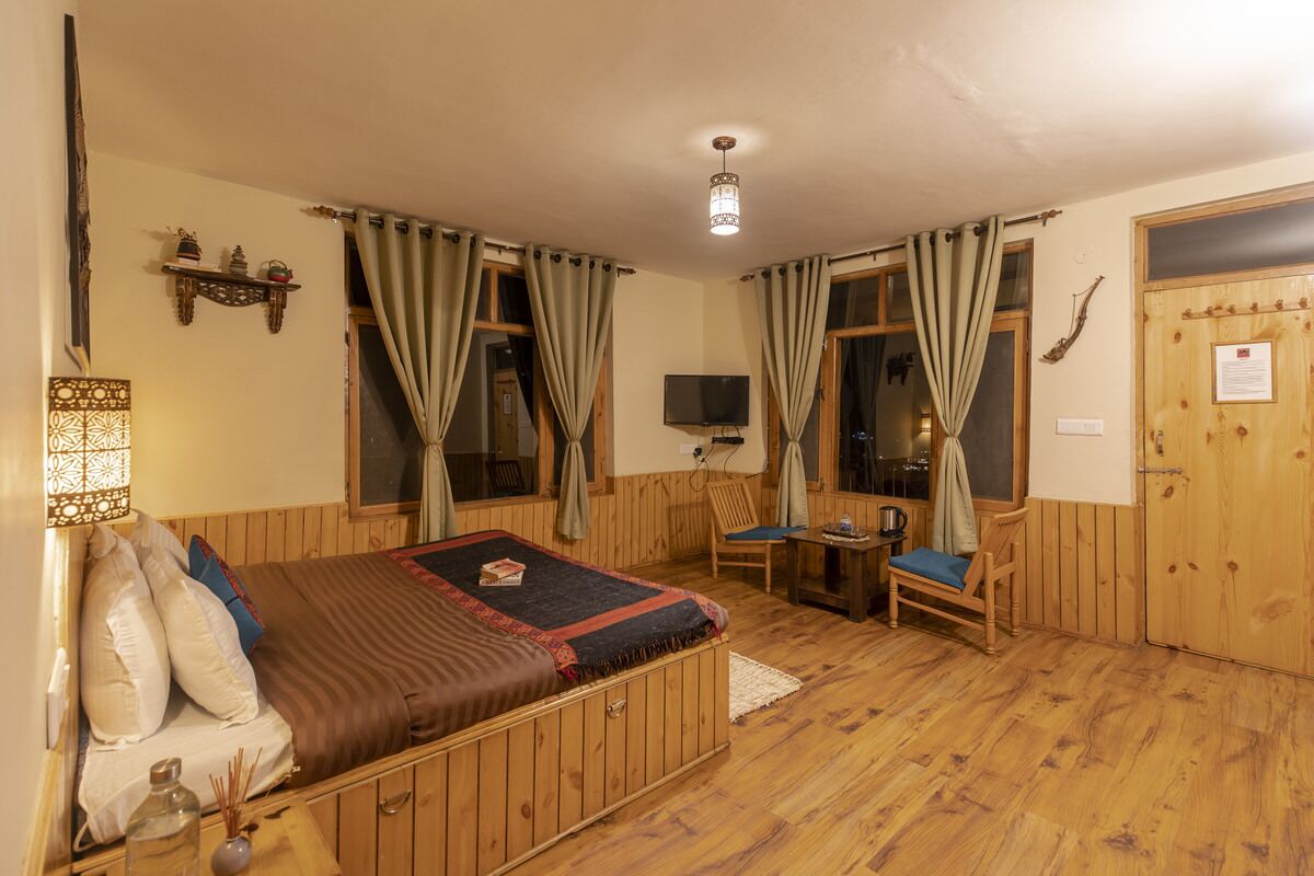 Een gezellige kamer met een bed, een stoel, een klein tafeltje en een televisie.