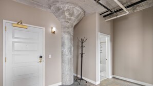 Un pasillo con una puerta blanca, un perchero y un baño visible a través de una puerta abierta.