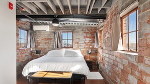 A bedroom with a bed, a desk, and a window. - The Nelson Lofts Penthouse (2BR) (Davenport)