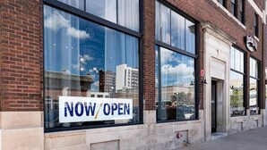 Un bâtiment en briques doté de grandes fenêtres et d’une enseigne indiquant « OUVERT MAINTENANT ».