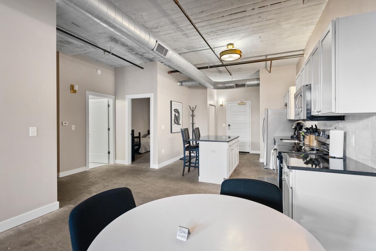 A modern kitchen with white cabinets, a central island, and stainless steel appliances.