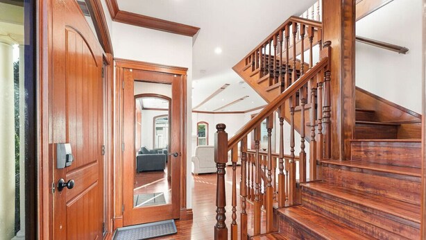 Un escalier en bois avec une rampe et une porte avec une boîte aux lettres sur le côté gauche.