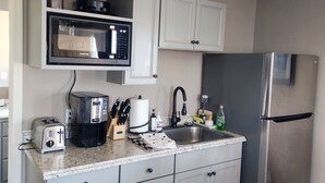 A kitchen with white cabinets, a stainless steel refrigerator, a coffee maker, a toaster, and a sink. - 3 bedroom 1 bath above garage guest house (Shoshone)