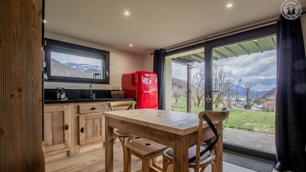 Una cocina moderna con armarios de madera, una mesa de comedor y un refrigerador rojo.