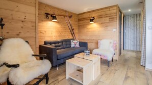 Una habitación acogedora con paredes de madera, un sofá, una silla y una pequeña mesa.
