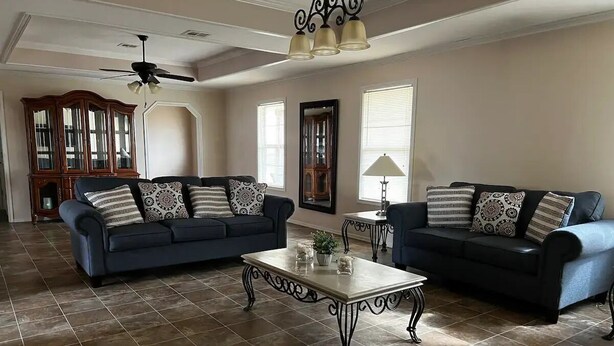 A spacious living room with two sofas, a coffee table, and a ceiling fan.