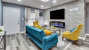 A living room with a sofa, armchairs, a TV, and a stone wall. - Inviting Savannah Home w/ Yard: 3 Mi to Downtown! (Savannah)