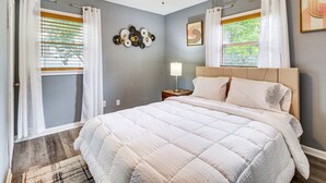 A bedroom with a bed, a ceiling fan, a nightstand with a lamp, and a window with curtains. - Inviting Savannah Home w/ Yard: 3 Mi to Downtown! (Savannah)