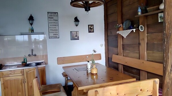 Una cocina rústica con armarios de madera, una mesa de comedor de madera con bancos y una repisa con utensilios de cocina.